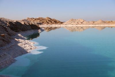 Scenic view of salt lake and mountains against clear blue sky