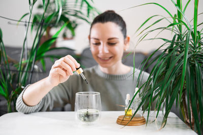 Woman putting essential oil in glass at home