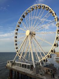 Ferris wheel by sea against sky