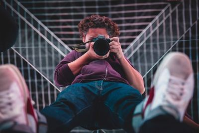 Midsection of man holding camera while sitting outdoors