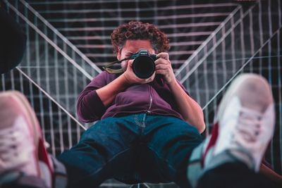 Midsection of man holding camera while sitting outdoors