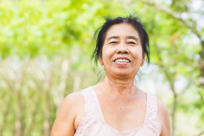 Old asian woman smiling with happy face standing outdoor with nature background