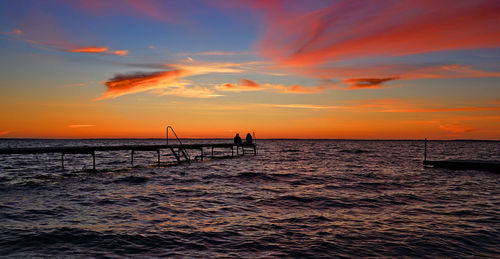 Silhouette people on beach against sky during sunset