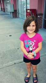 Smiling girl standing against wall