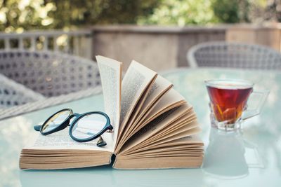 Close-up of eyeglasses and book with drink on table
