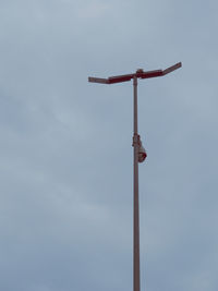 Low angle view of cross on pole against sky