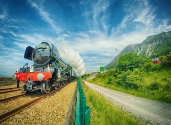 Railroad tracks against cloudy sky