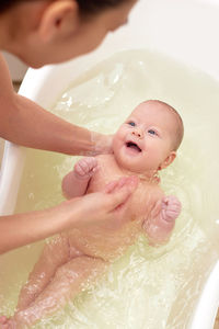 Mother bathing baby girl in bathtub