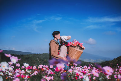 Young woman holding flower in basket on field