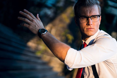 Portrait of young man holding eyeglasses