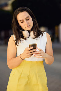 Young woman using mobile phone while standing outdoors