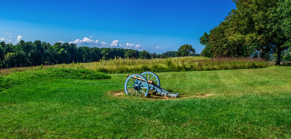 Bicycle on field against blue sky