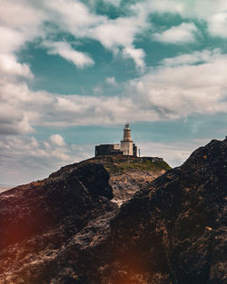 Lighthouse by sea against sky during sunset