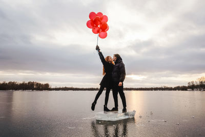 Rear view of couple standing on water against sky