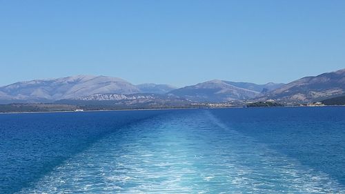 Scenic view of lake and mountains against clear blue sky