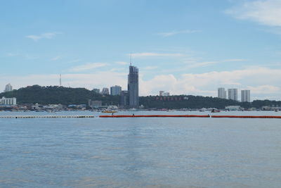 View of buildings by river against sky in city