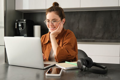 Businesswoman using laptop while sitting on table