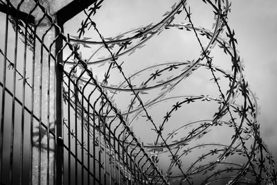 Low angle view of barbed wire fence against sky