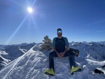 Man skiing on snow covered mountain against sky