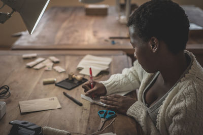 Side view of young african woman working in workshop