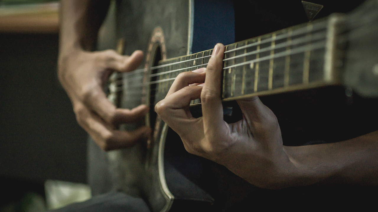 MIDSECTION OF PLAYING GUITAR AT MUSIC CONCERT