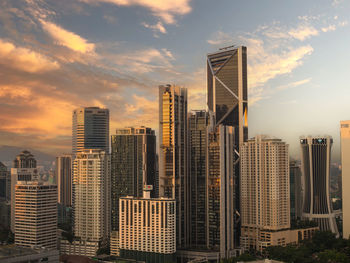 Modern buildings in city against sky during sunset