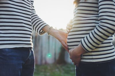 Midsection of man touching pregnant woman belly while standing outdoors