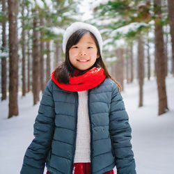 The joy of the winter. portrait of smiling young girl in a snowcapped forest, wearing warm clothes.