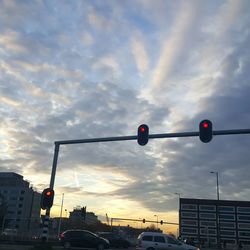 Low angle view of traffic signal against cloudy sky