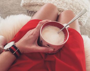 Low section of woman holding coffee cup on table