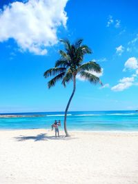 Man carrying woman in arms at beach against sky on sunny day