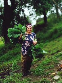 Portrait of smiling woman standing on land in forest