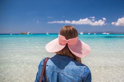 Rear view of woman with pink hat standing on beach