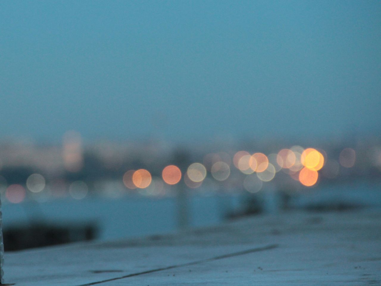 DEFOCUSED IMAGE OF ILLUMINATED CITY AGAINST SKY AT DUSK