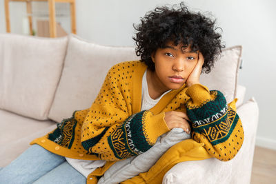 Portrait of young woman sitting on sofa at home