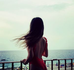 Rear view of woman looking at sea against sky