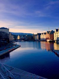 River and buildings against sky at dusk