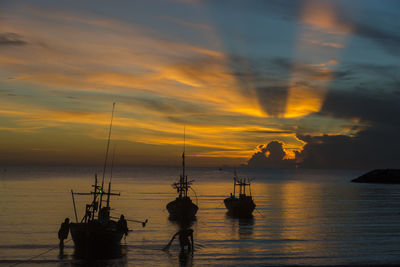 Silhouette of fishing boats on sea against sky during sunset