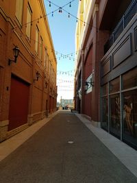 Road amidst buildings against clear sky