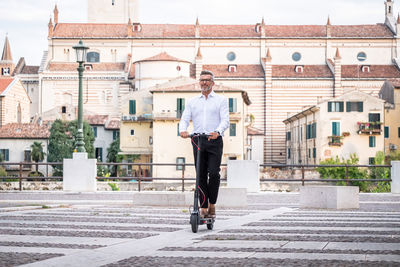 Full length of businessman riding electric scooter
