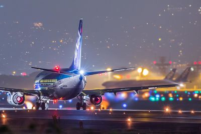 Airplane on runway against sky at night