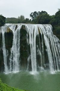 Scenic view of waterfall against sky