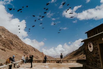 People flying birds against sky