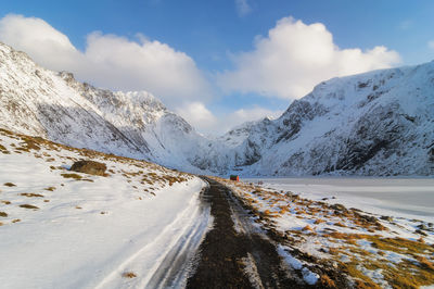 Road amidst snowcapped mountains against sky