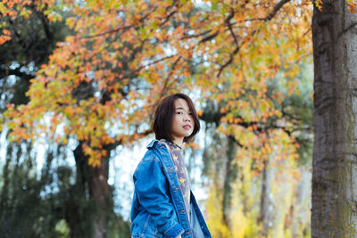 Portrait of mid adult woman standing against autumn trees