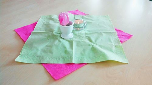 Pink tulip in eggcup on tissue paper over table