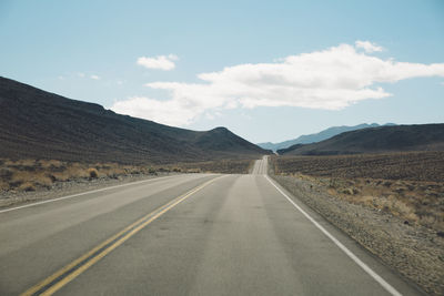 Road by mountains against sky