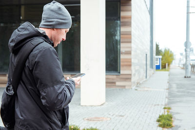 Side view of young man standing on street