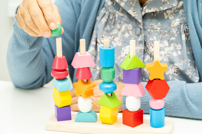 Midsection of woman holding multi colored toys against white background