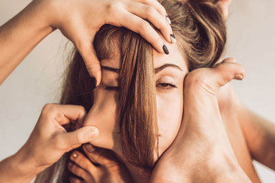 Cropped image of people hitting woman against white background